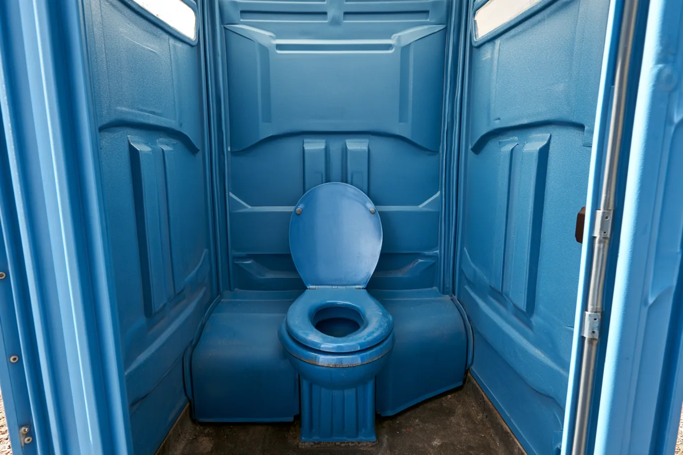 An ordinary blue molded portable toilet interior before any upgrade: plain walls, standard seat, no ventilation